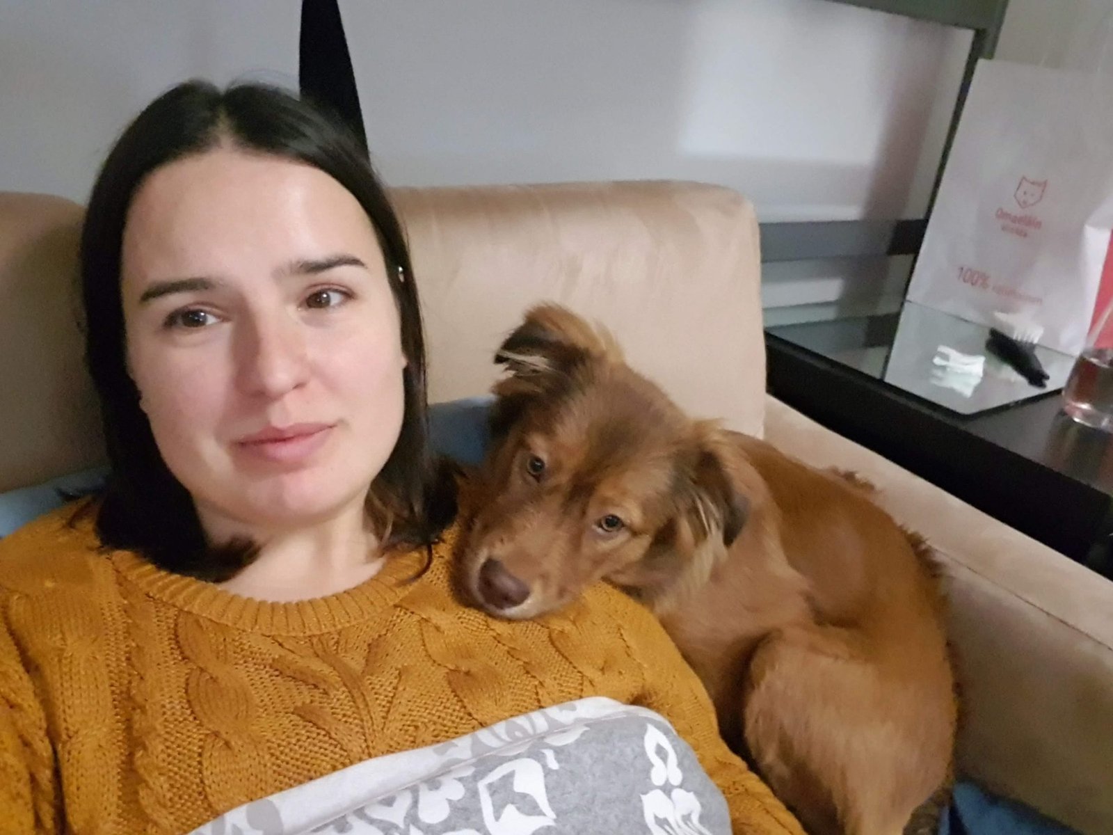 Ángela sentada en el sofá con su perro apoyado en el hombro